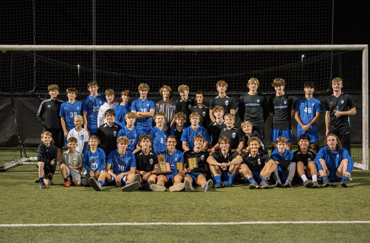 The Highlands Boys Varsity soccer team smiles in the goal after winning a district championship. 